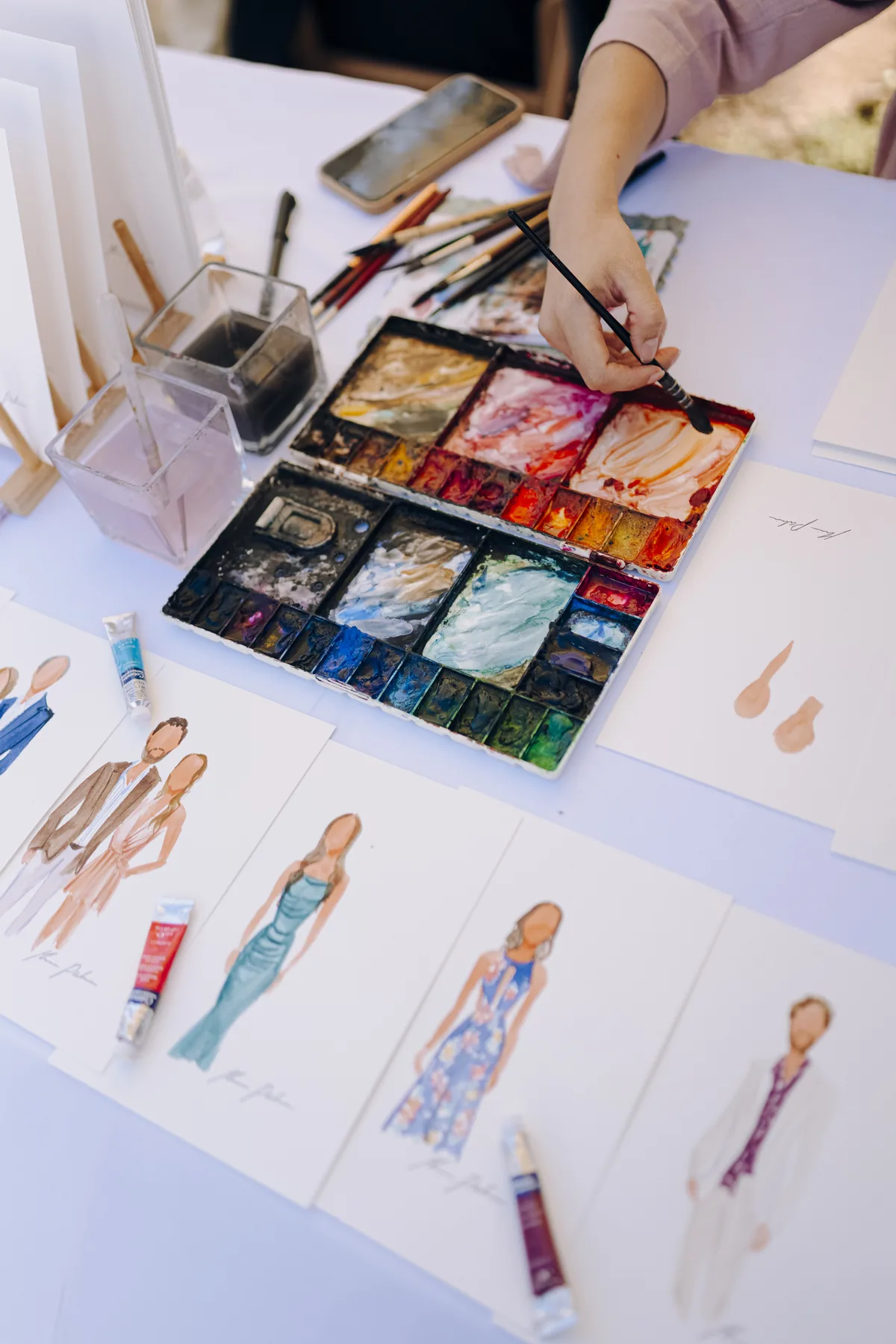 Detalle de materiales y retratos en acuarela pintados en vivo